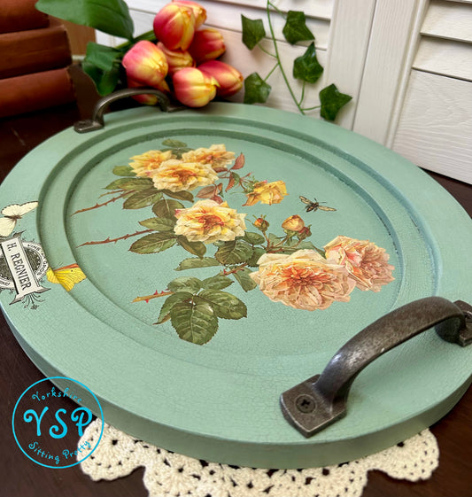 Oval decorative tray with floral design on a table with flowers in the background
