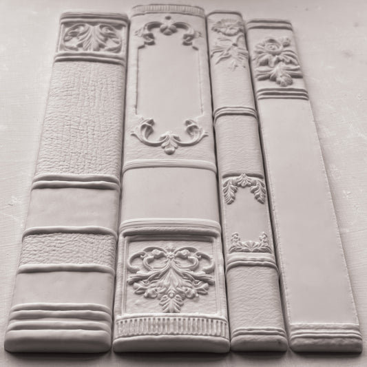 Decorative white bookends with intricate designs on a grey surface from Iron Orchid Designs Bookish mould