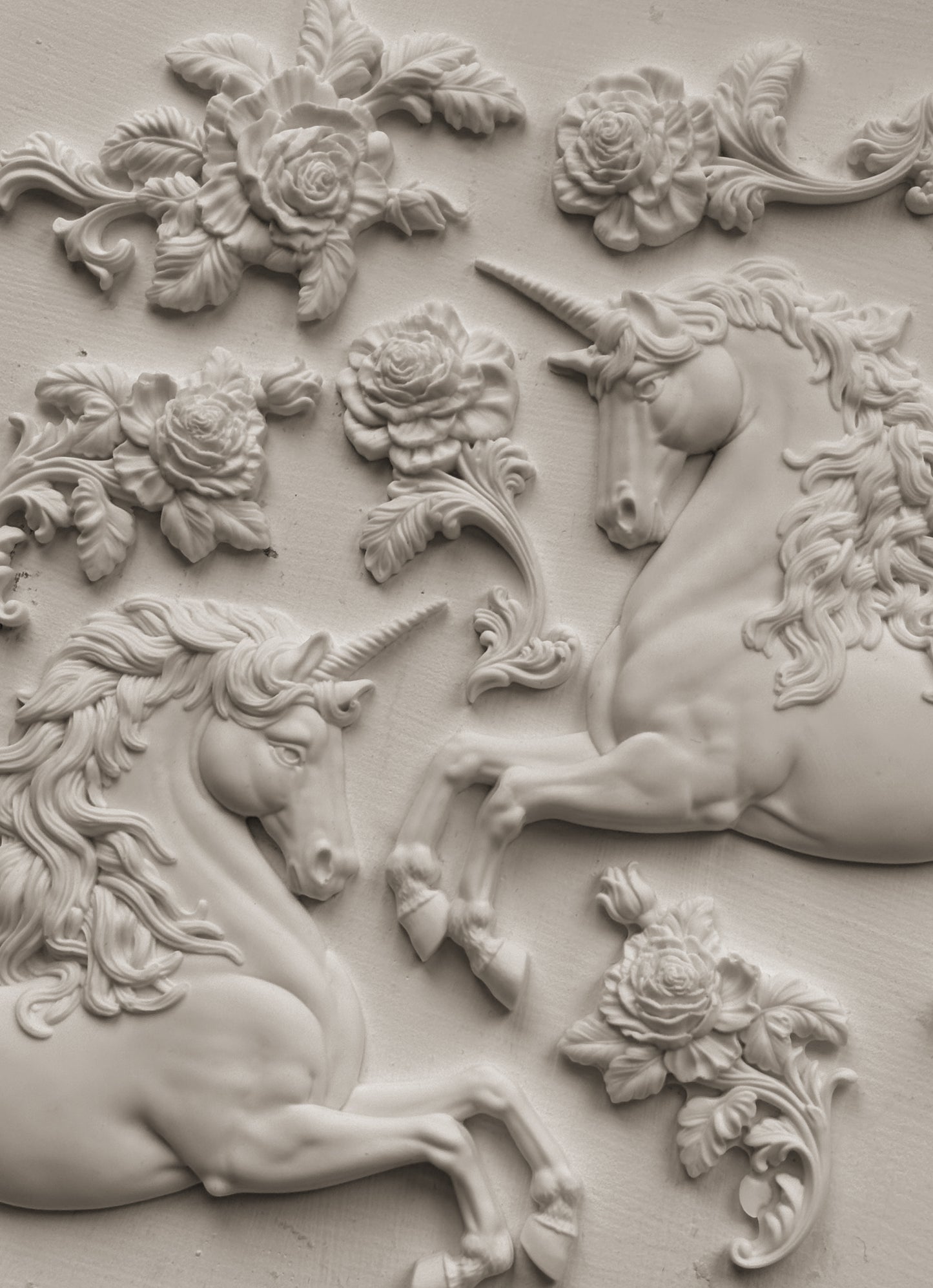White clay castings of Iron Orchid Designs Unicorns and flowers on a white background