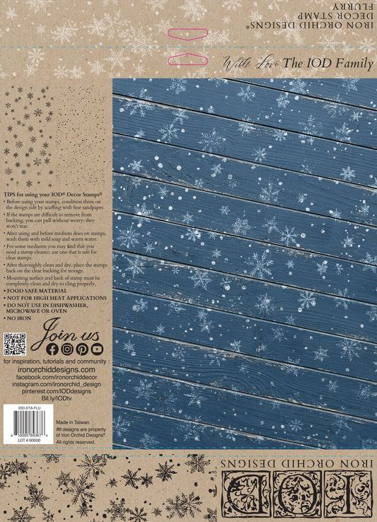 Back cover of an Iron Orchid Designs 'With Fox The IOD Family' decorative stamp book, featuring a blue wood-grain panel with white snowflakes on the right and product details, barcode, and branding on the left. Flurry stamp