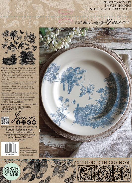 Decorative stamped plate with blue bird design on a rustic wooden surface, surrounded by nature-themed elements.