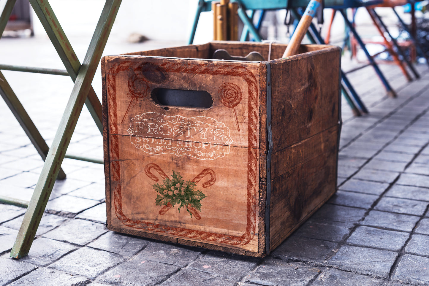 An image showing a wooden box that has been stamped with Iron Orchid Designs Frosty's Sweet Shoppe stamp. The box is standing on a tiled floor next to a table.