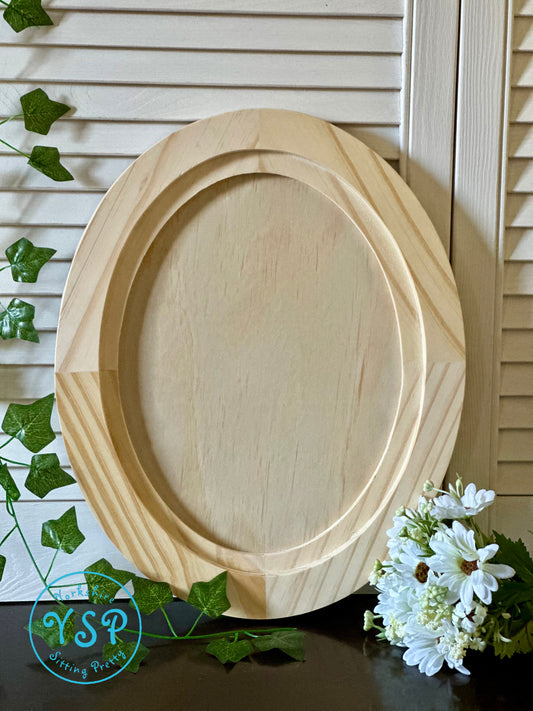 Wooden oval craft blank on a surface with greenery and flowers in the background by Iron Orchid Designs