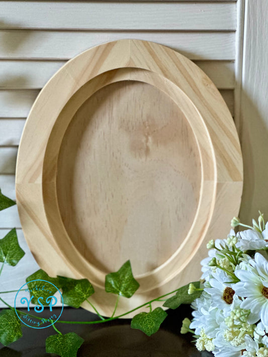 Wooden oval craft blank on a surface with greenery and flowers by Iron Orchid Designs