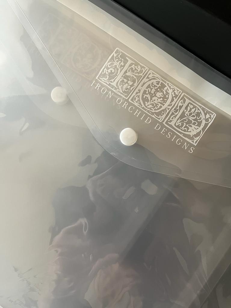 A close up image of Iron Orchid Designs semi-transparent Stamp Envelopes on a dark surface showing the popper fastening