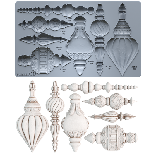 A silicone mold tray at the top shows multiple ornate architectural ornament cavity designs with small printed measurements. Below the tray are the corresponding molded ornament pieces in an off-white/ivory finish, arranged on a plain white background. Baubles mould by Iron Orchid Designs.