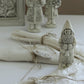 A styled tabletop scene with cream-colored fabric napkins tied with twine and small decorative Santa Claus figurines, including one in the foreground and two larger ones in the background.From Iron Orchid Designs.
