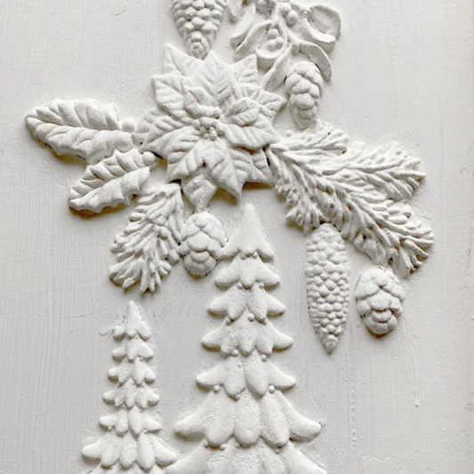 White embossed holiday wall decor featuring a poinsettia, holly, pinecones, and snowflake designs on a textured white background. Boughs of Holly Iron Orchid Designs