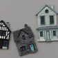 Three miniature decorative house figurines in different architectural styles displayed on a plain beige background. Charlbury Lane From Iron Orchid Designs.