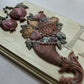 A close-up of a carved wooden decorative plaque featuring pomegranates, flowers, and a basket motif, with part of a large letter 'H' visible on the right side. Cornucopias mould. From Iron Orchid Designs.