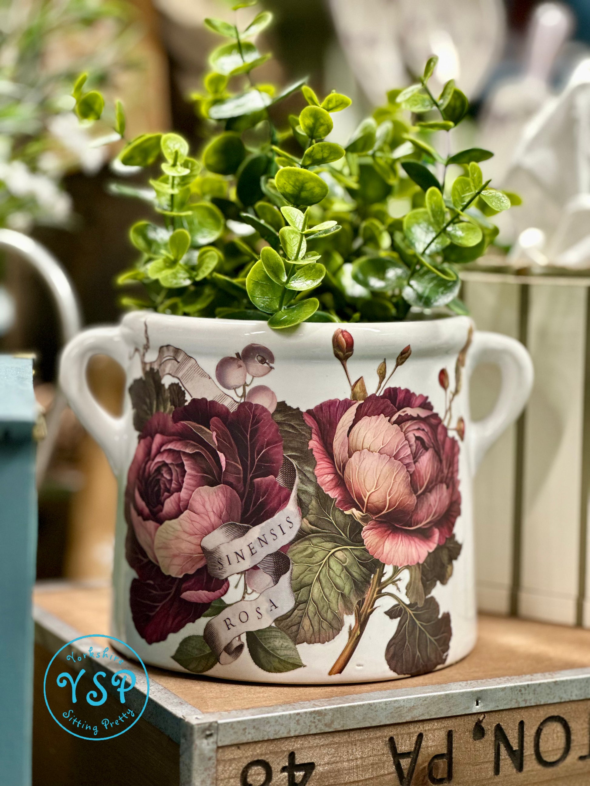 Decorative white ceramic flower pot with floral design on a wooden surface