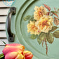 Oval green tray with floral design and pink tulips in the foreground