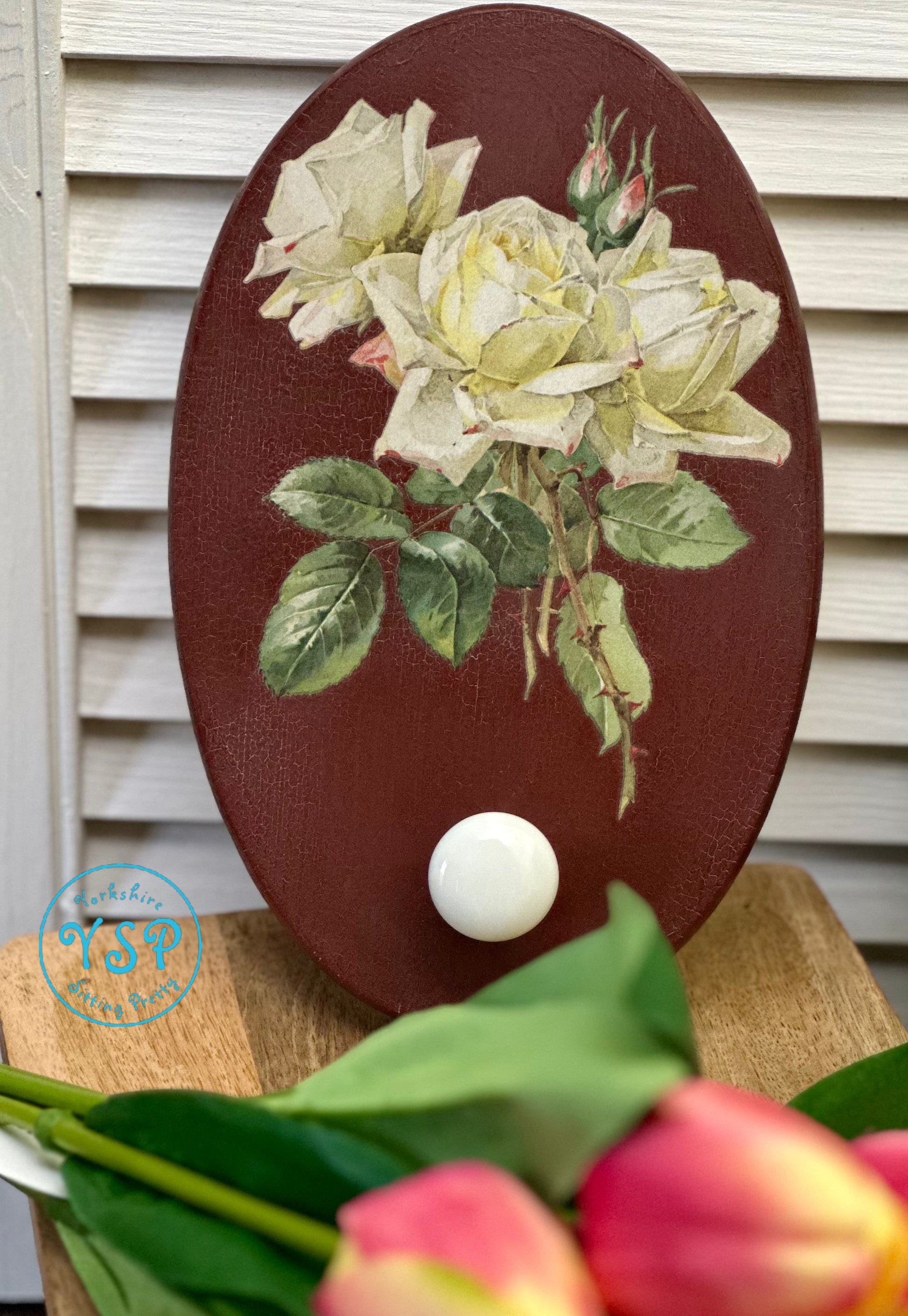 Decorative wall hanger/hook with floral design on a white wooden background