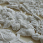 White clay floral and leaf relief sculpture on a light beige background. Hazel and Bay mould. From Iron Orchid Designs.