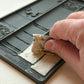 Hand using a tool to shape a small block of material on a decorative mould from Iron Orchid Designs Bookish mould