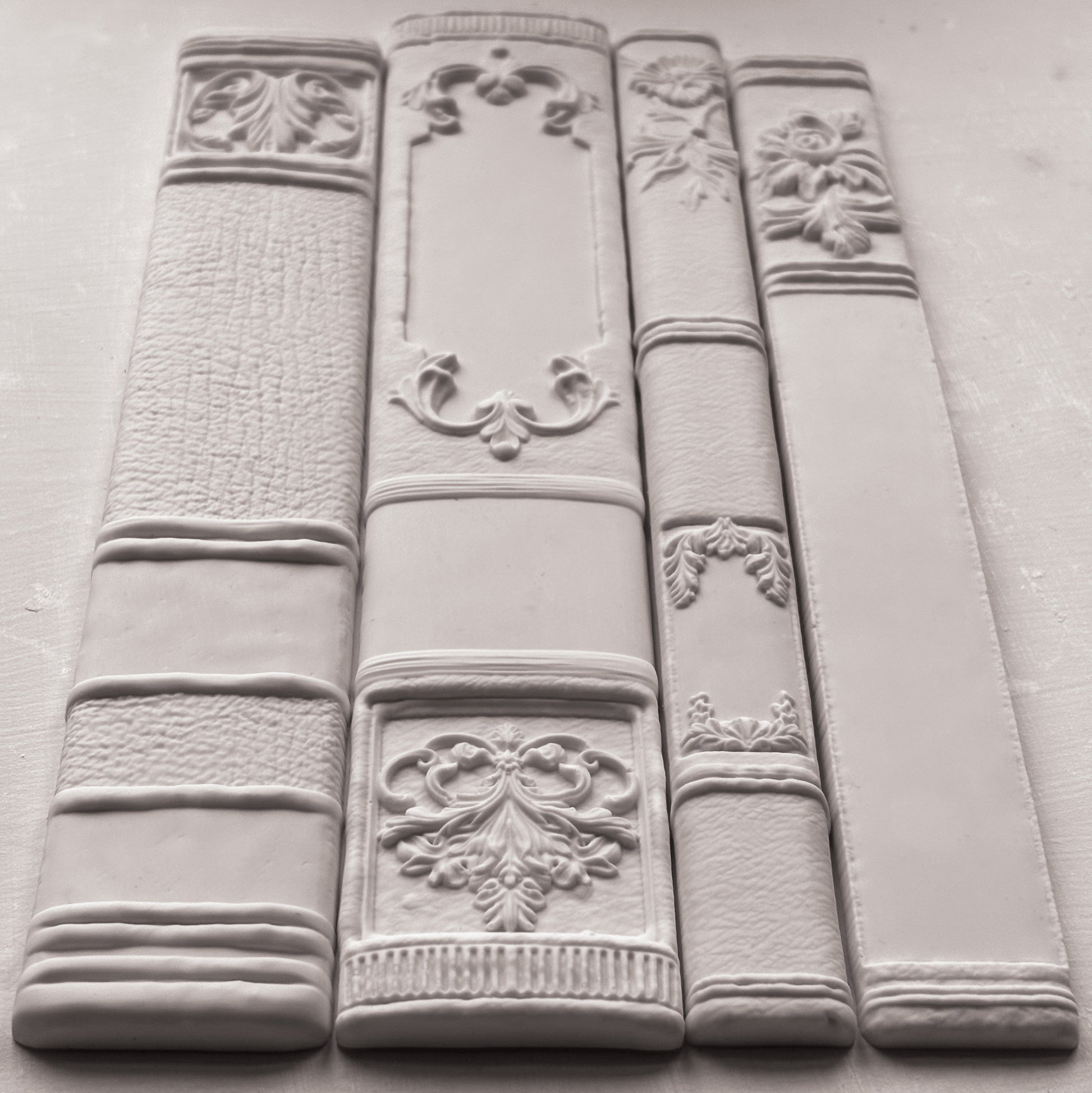 Decorative white bookends with intricate designs on a grey surface from Iron Orchid Designs Bookish mould