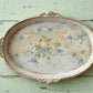 Decorative oval tray with floral design on a rustic wooden surface
