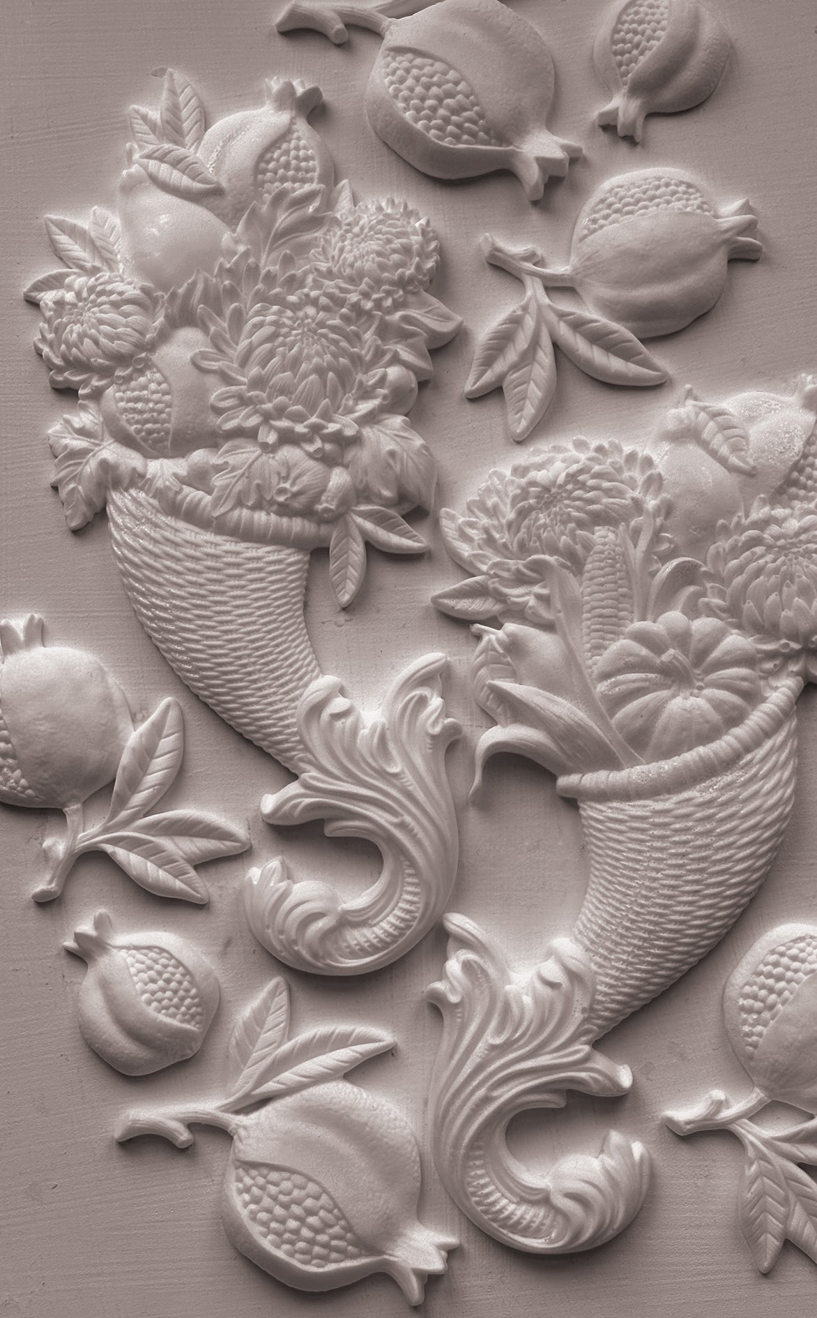White clay decorative wall relief featuring pomegranate motifs and floral baskets on a textured light gray surface. Cornucopias mould. From Iron Orchid Designs.