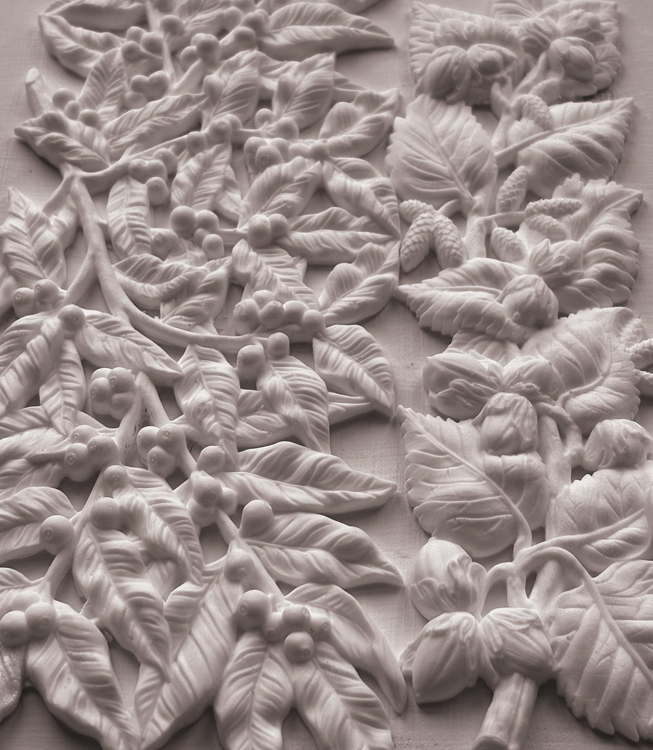 White carved floral and leaf wall panel with raised botanical relief details on a matching background. From Iron Orchid Designs.