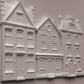 White clay miniature building pieces for dioramas, featuring detailed house designs with windows, doors, and textured brick patterns, arranged on a light gray background. Old Colchester Road Mould From Iron Orchid Designs.