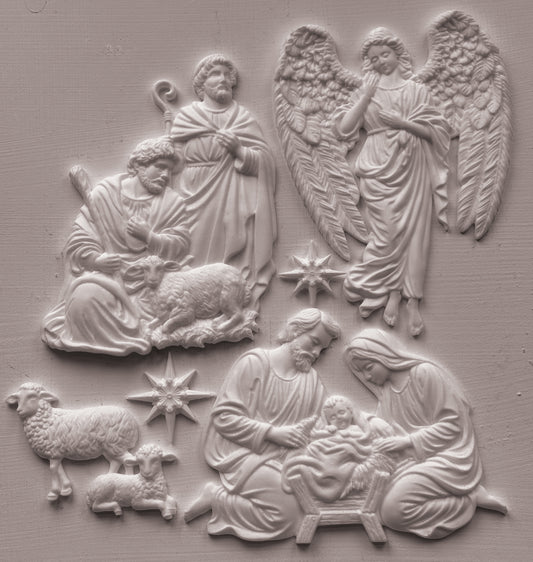 White clay castings depicting the Holy Family, angels, and sheep on a textured light gray background. Silent Night mould from Iron Orchid Designs.
