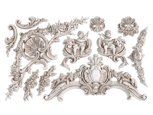 White clay castings of cherubs, swirls and decorative elements from Iron Orchid Designs Cadre Mould