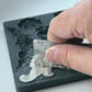 Person using a ruler to smoothout clay in a a decorative mould on a white surface - from Iron Orchid Designs Cadre Mould