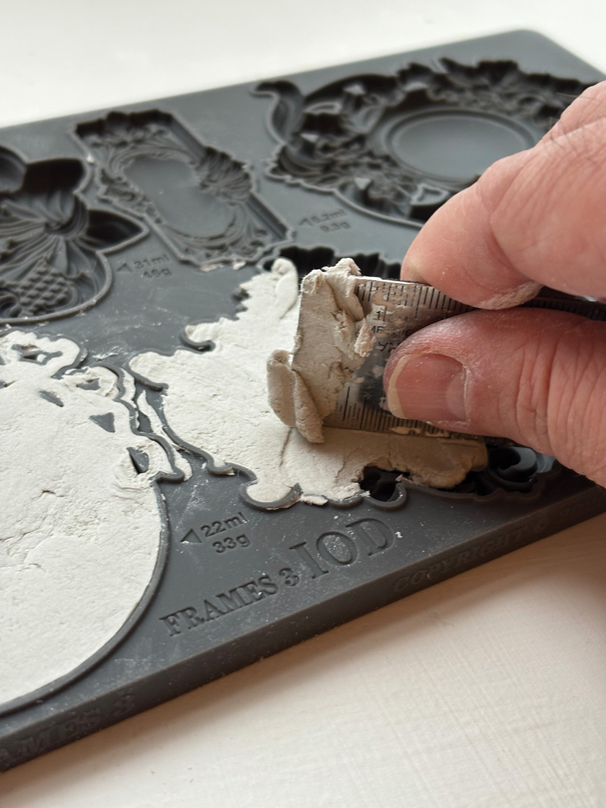 Person using a tool to remove excess material  from Iron Orchid Designs Frames 3 Mould