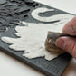 Hand using a metal ruler to fill a silicone mould with air dry clay. Taken  from Iron Orchid Designs Swans Mould