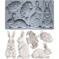 Grey silicone rabbit mould from Iron Orchid Designs above white castings from Les Lapins mould. All on a white background