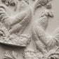 White clay castings of Iron Orchid Designs Chanticleer mould on a white background. two decorative roosters on floral plinths with swirls