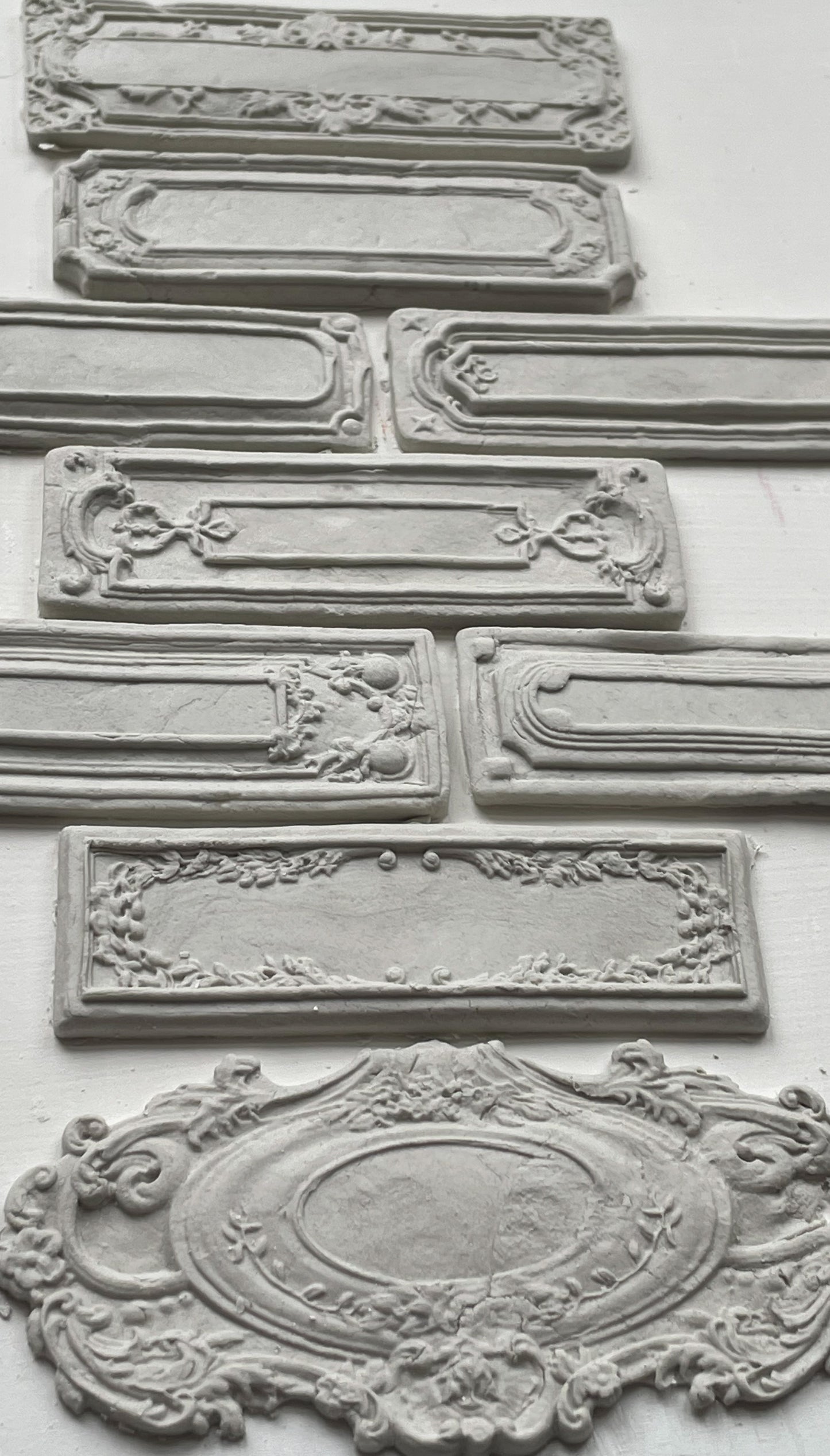 White clay castings of Iron Orchid Designs Conservatory Labels castings laid on top of a white surface