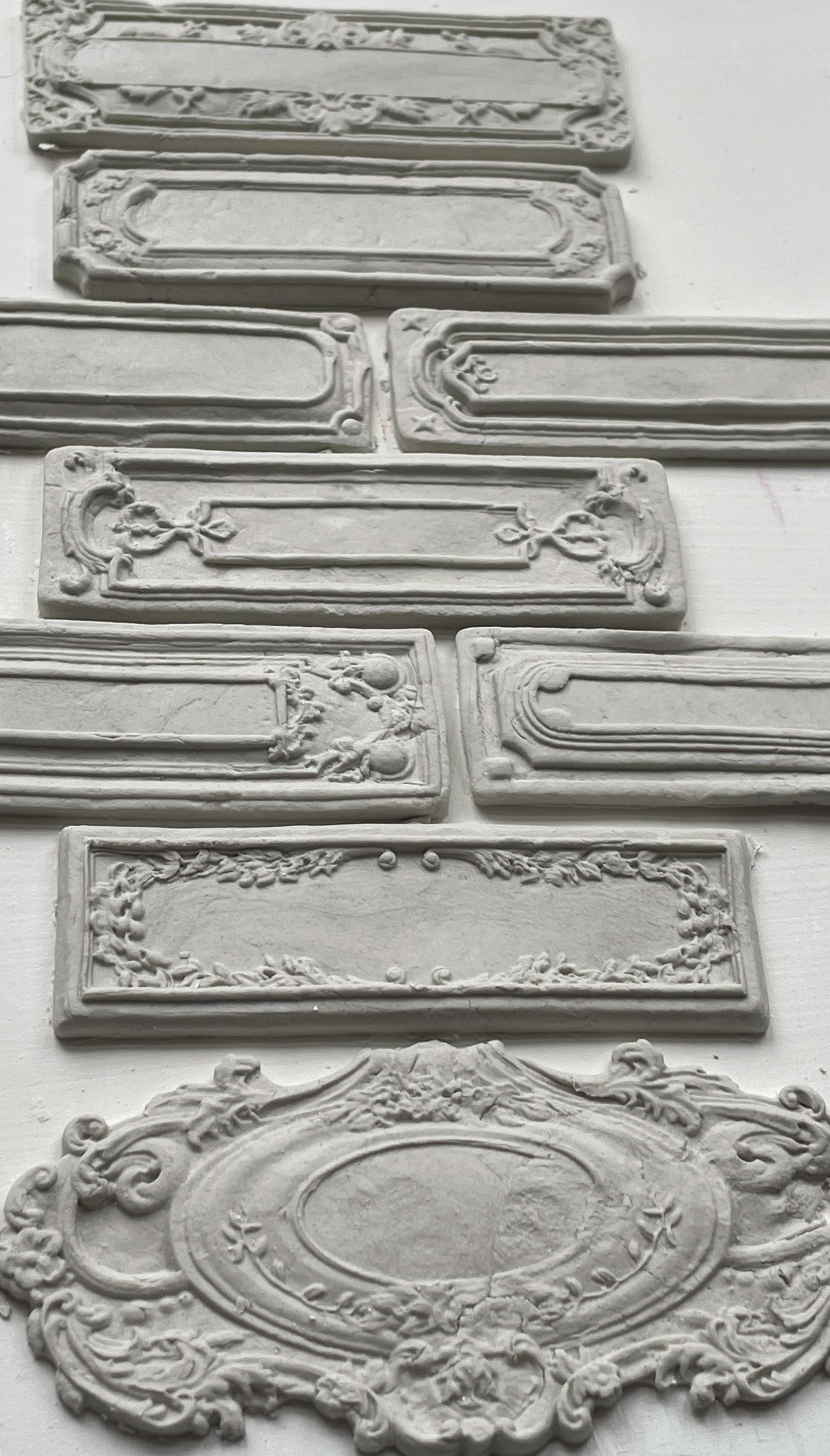 White clay castings of Iron Orchid Designs Conservatory Labels castings laid on top of a white surface