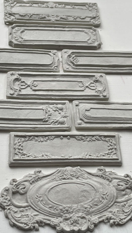 White clay castings of Iron Orchid Designs Conservatory Labels castings laid on top of a white surface