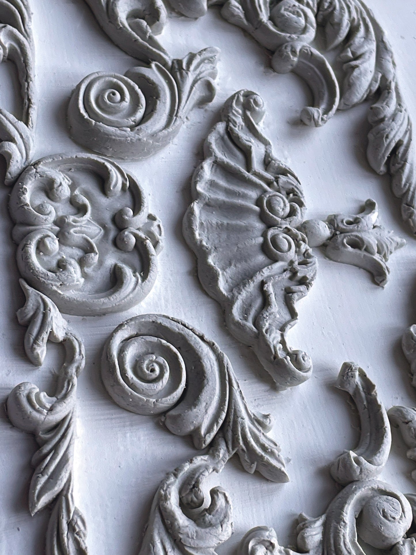 A close up of white castings from Iron Orchid Designs Dainty Flourishes mould. The castings are on a white background