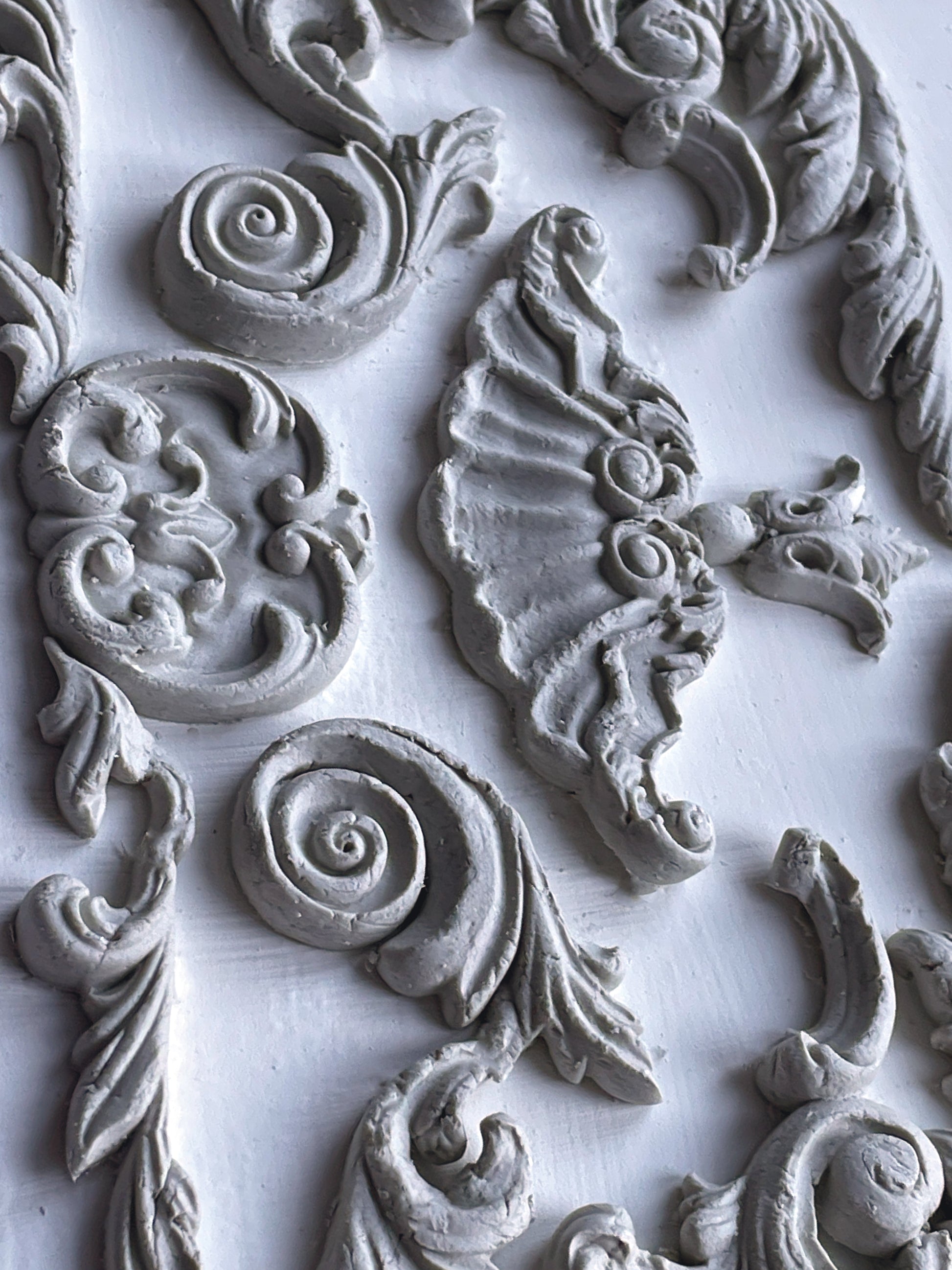 A close up of white castings from Iron Orchid Designs Dainty Flourishes mould. The castings are on a white background