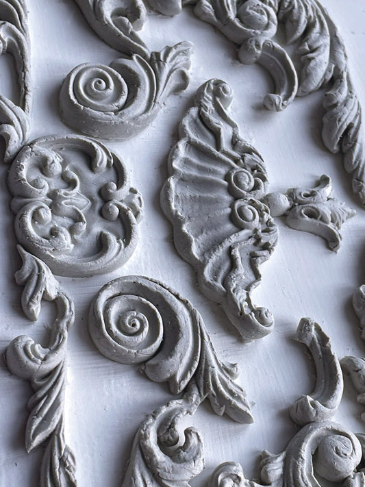 A close up of white castings from Iron Orchid Designs Dainty Flourishes mould. The castings are on a white background