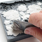 A close up image of a hand scraping excess clay using a metal ruler from Iron Orchid Designs Felicite mould