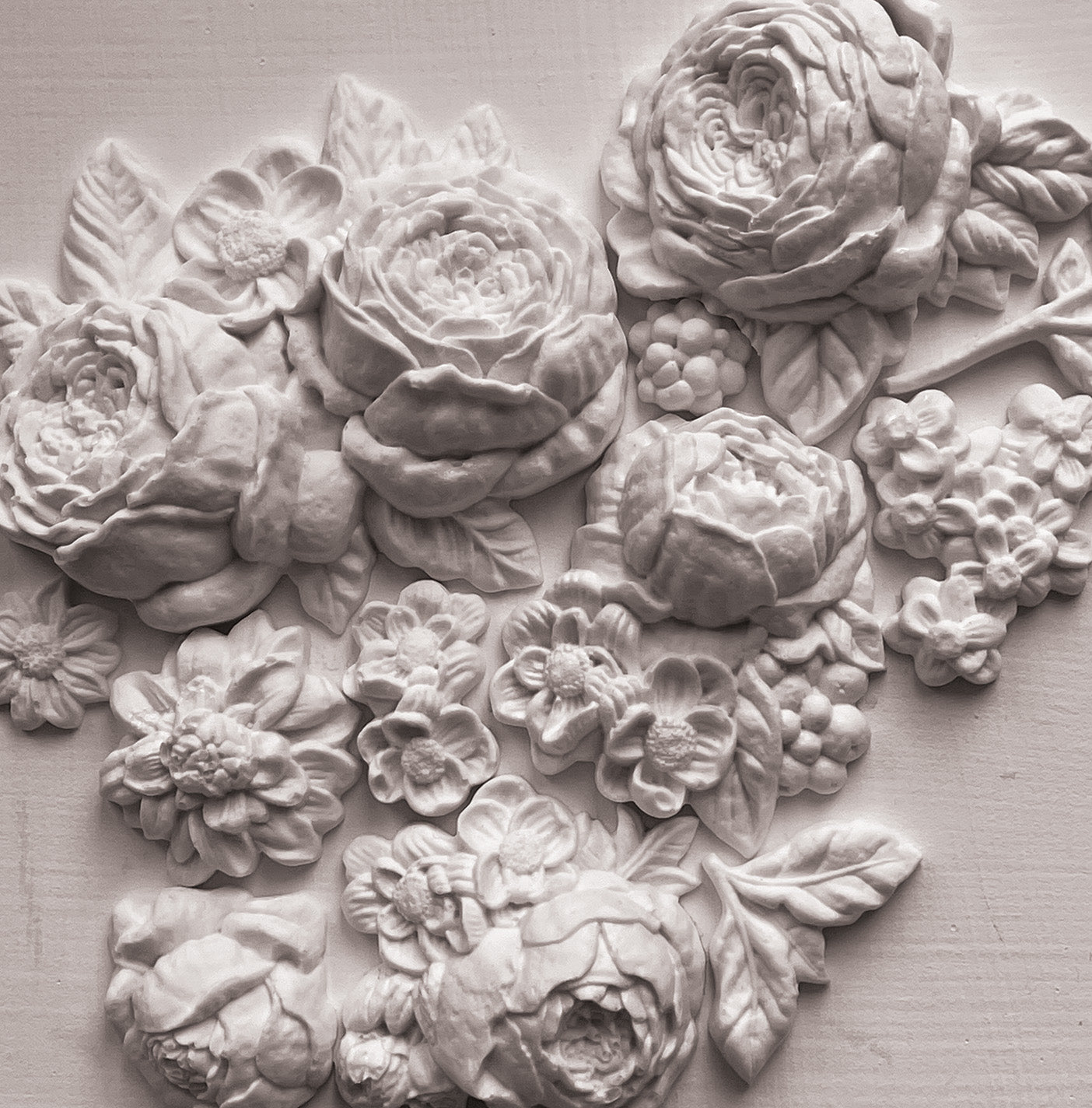 A close up image of white castings from Iron Orchid Designs Felicite mould. The flowers have been arranged into a cluster and are on a white background.