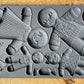 A grey-coloured decor mould by Iron Orchid Designs featuring gingerbread figures and holiday-themed patterns.