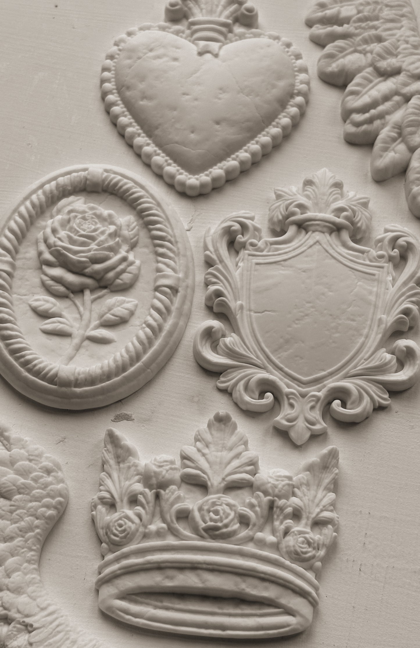 White clay castings from Iron Orchid Designs Heraldry mould on a white background
