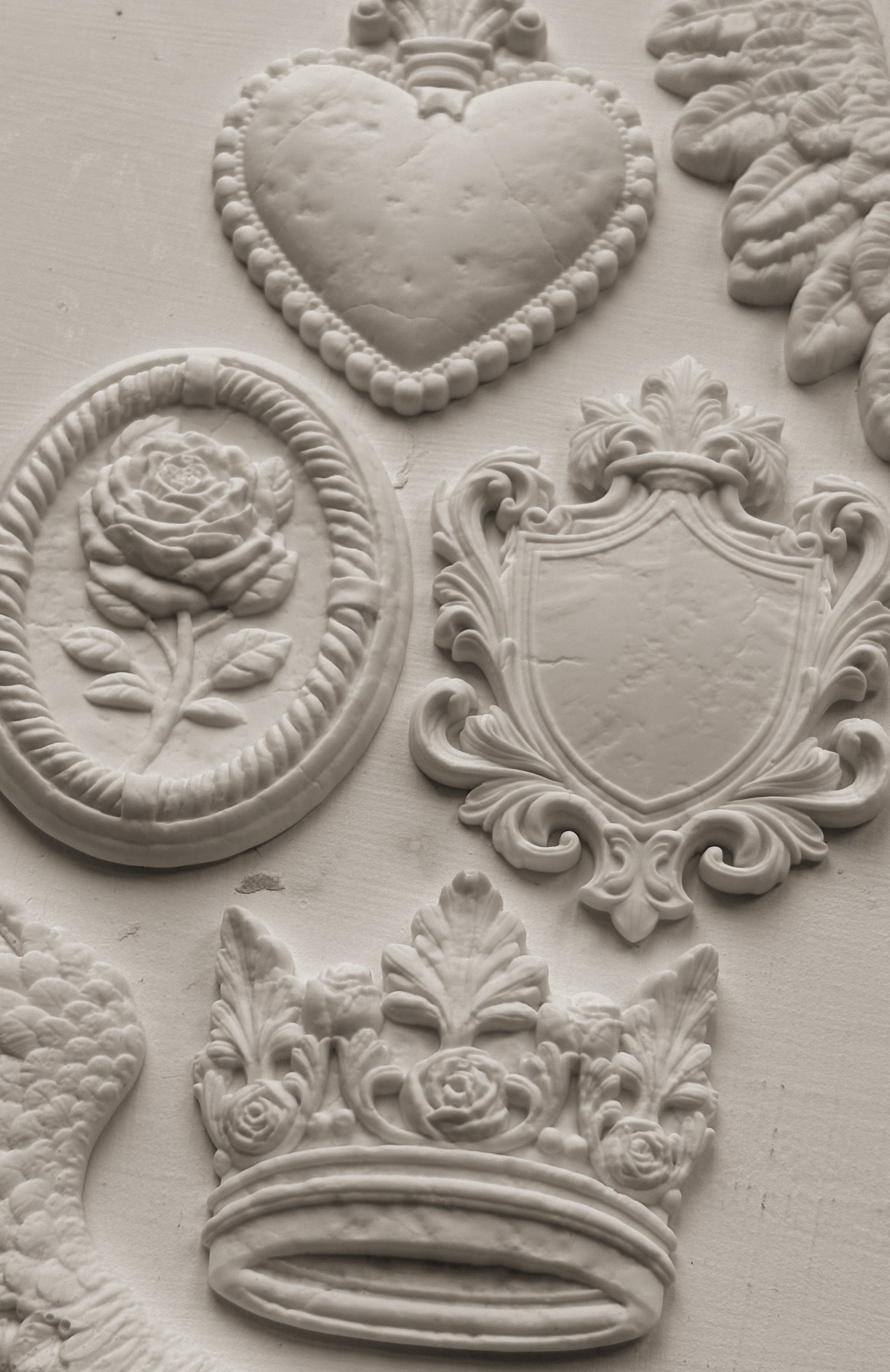 White clay castings from Iron Orchid Designs Heraldry mould on a white background
