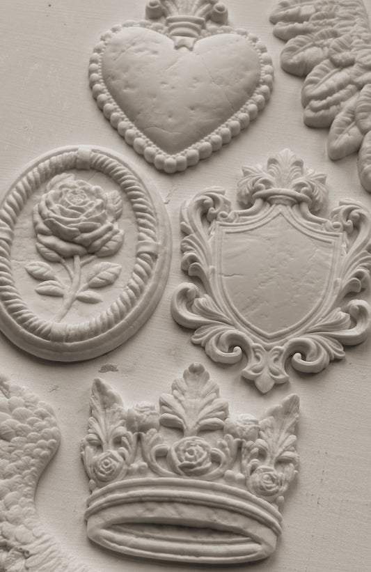 White clay castings from Iron Orchid Designs Heraldry mould on a white background