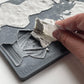 A close  up image of a hand removing excess clay from Iron Orchid Designs Invitation Only mould