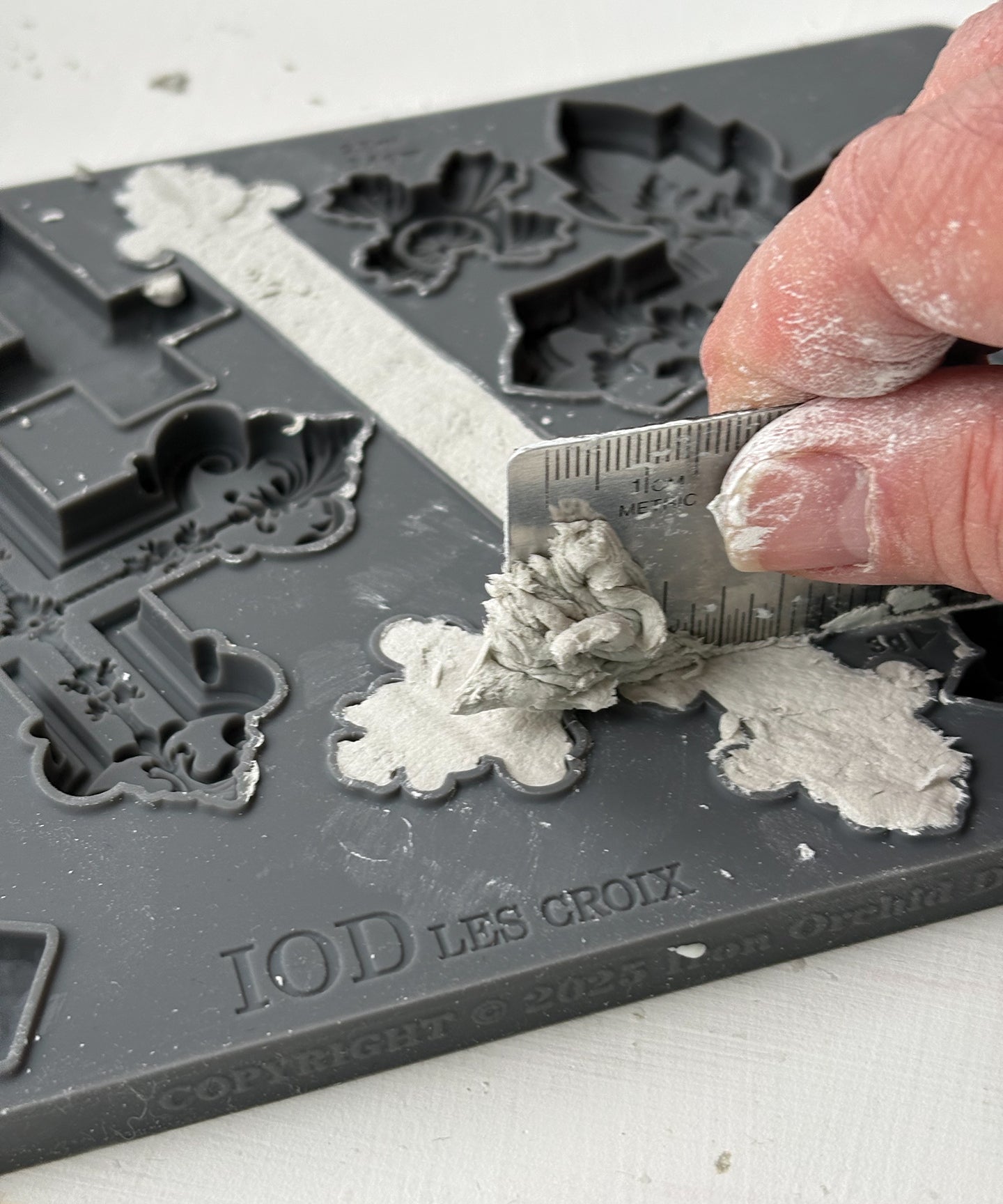 Person using a tool to press air dry clay into the Les Croix mould from Iron Orchid Designs 