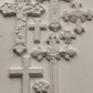 Decorative white clay cross castings from Iron Orchid Designs with intricate designs on a white background