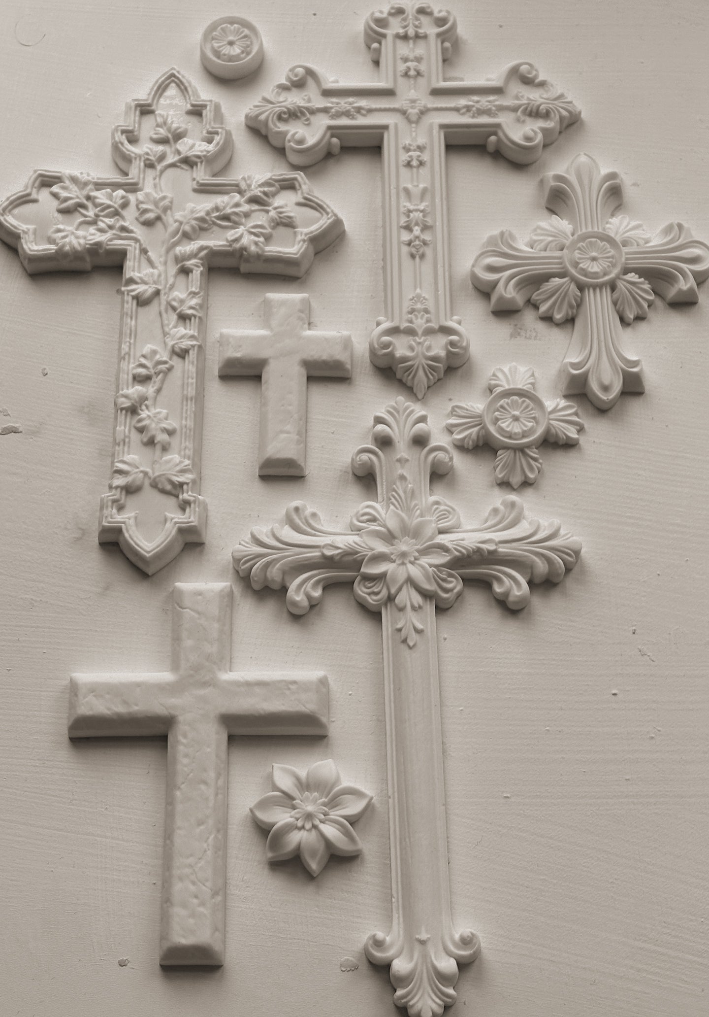Decorative white clay cross castings from Iron Orchid Designs with intricate designs on a white background