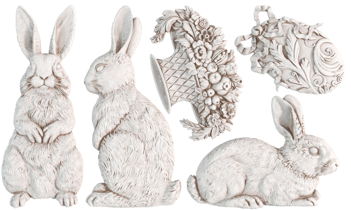 White clay castings of three rabbits , a basket and a decorative egg from Iron Orchid Designs Les Lapins mould. The castings are on a white background