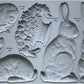 Grey silicone mould from Iron Orchid Designs. Les Lapins has three rabbits, a basket and an decorative egg.