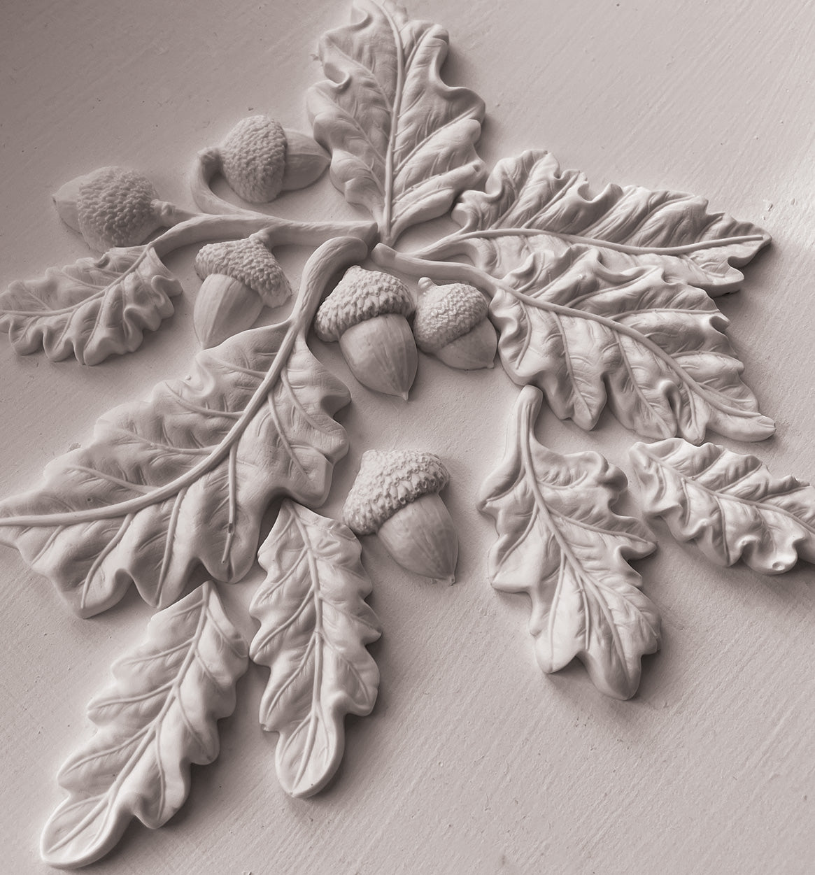 A close up images of white clay castings from Iron Orchid Designs Oak leaves and Acorns mould. The white castings are on a white background